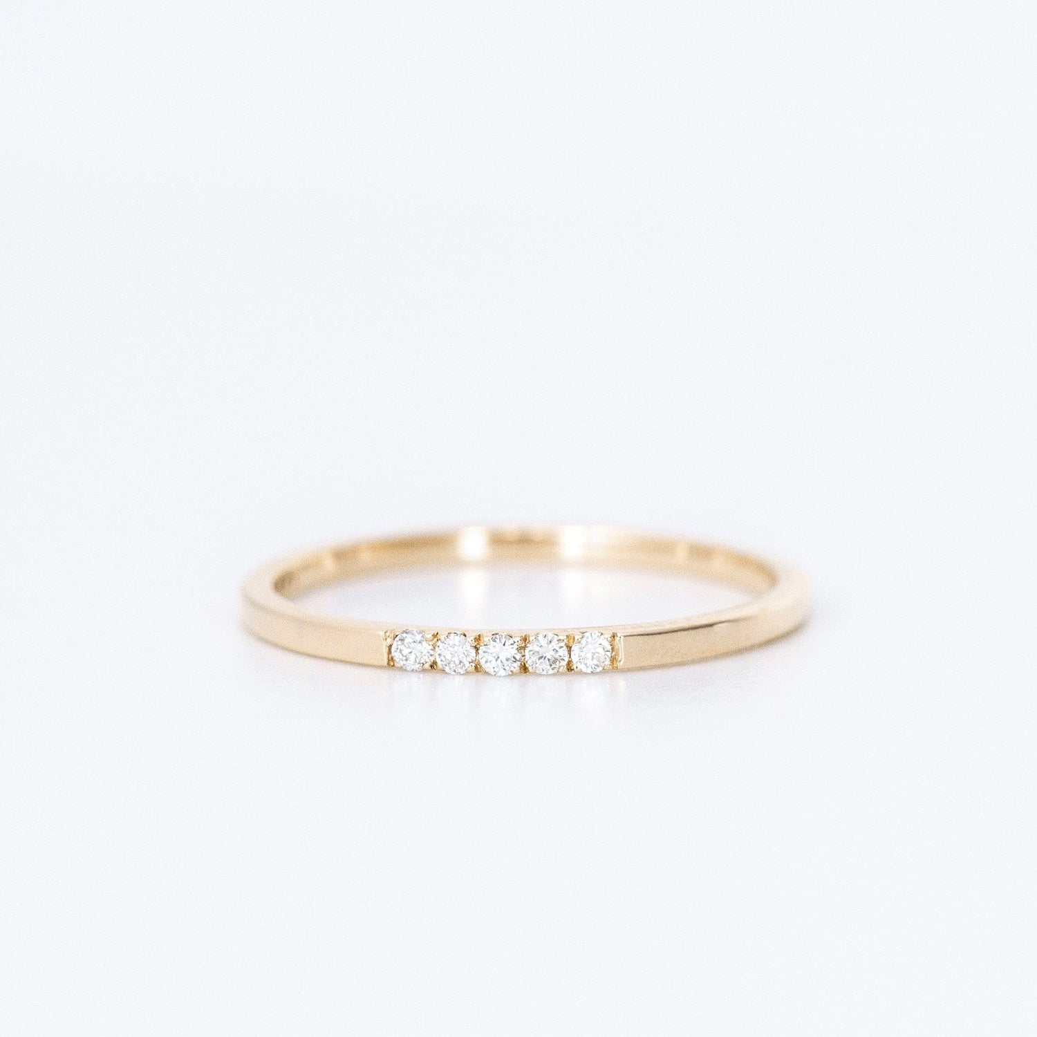 thin diamond wedding band with 5 small diamonds in yellow gold