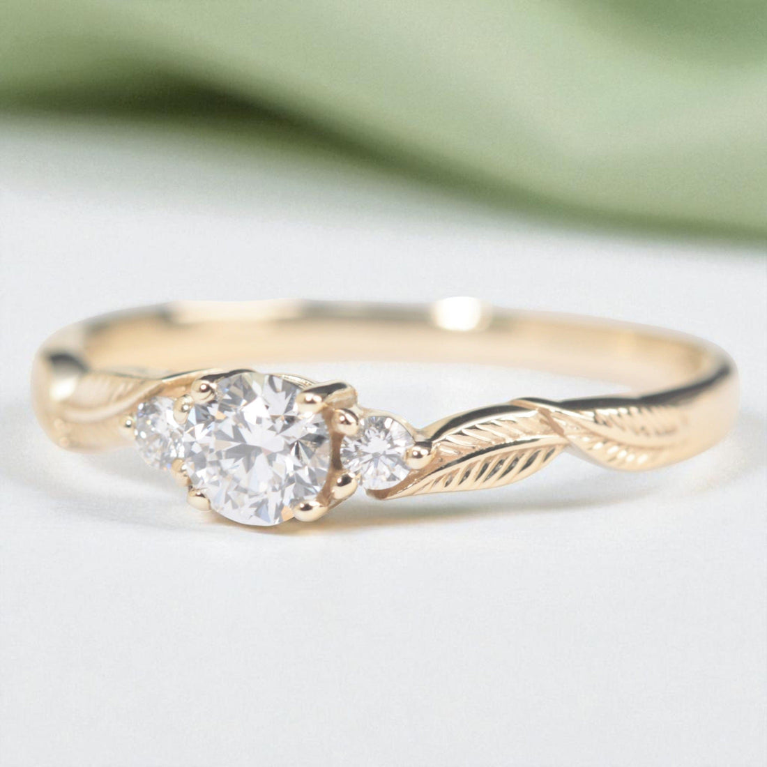 three-diamond-leaf_ngagement-ring-with-sage-background-Photoroom