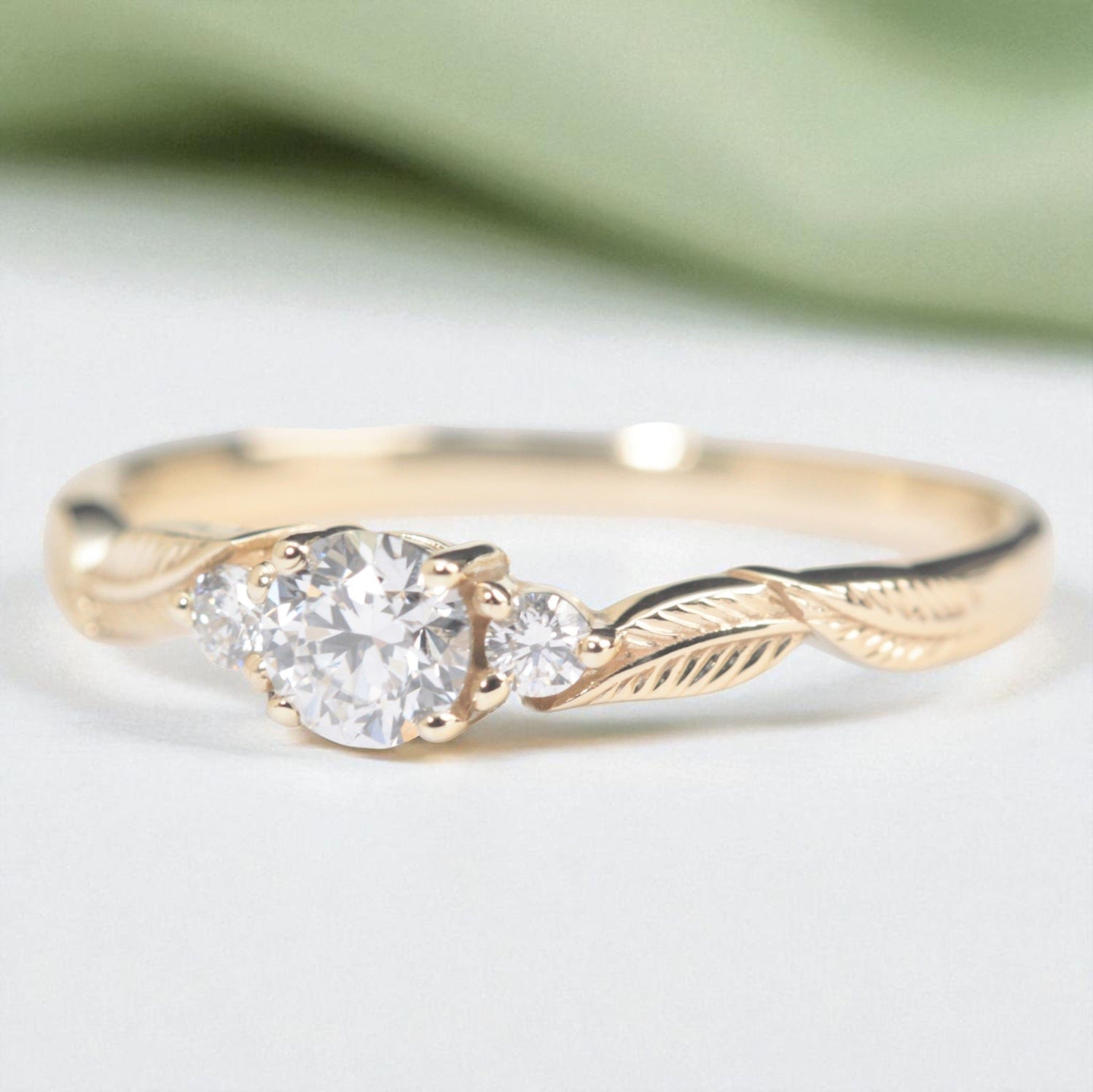 three-diamond-leaf_ngagement-ring-with-sage-background-Photoroom